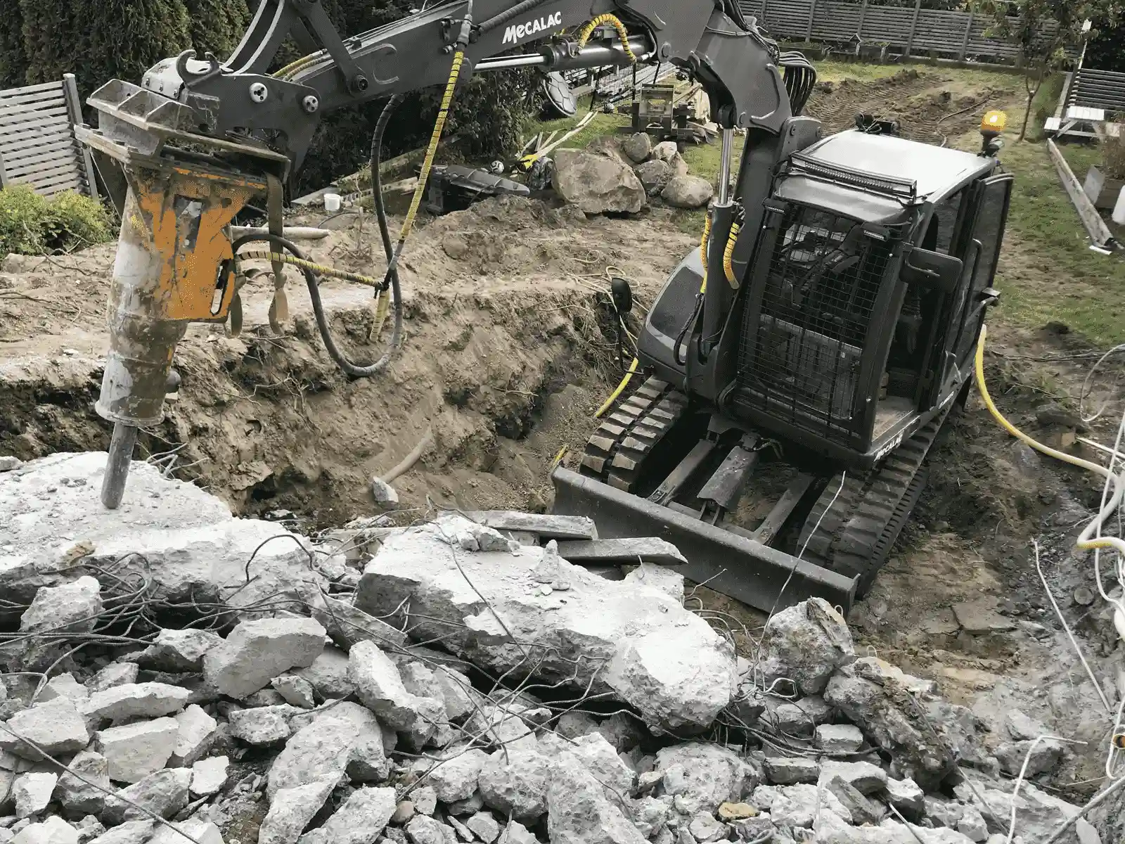 på bilden flisar en grävmaskin med hammare betong under rivningen av en källare i Djursholm